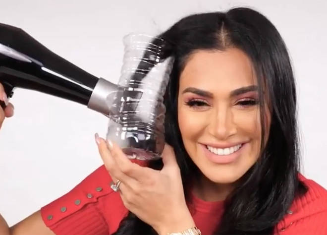 Huda Kattan curling her hair with a plastic bottle