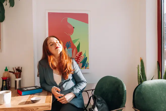 Woman sitting in a bedroom with plants and art