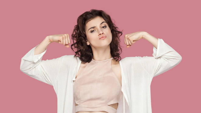 Woman flexing in front of a pink background